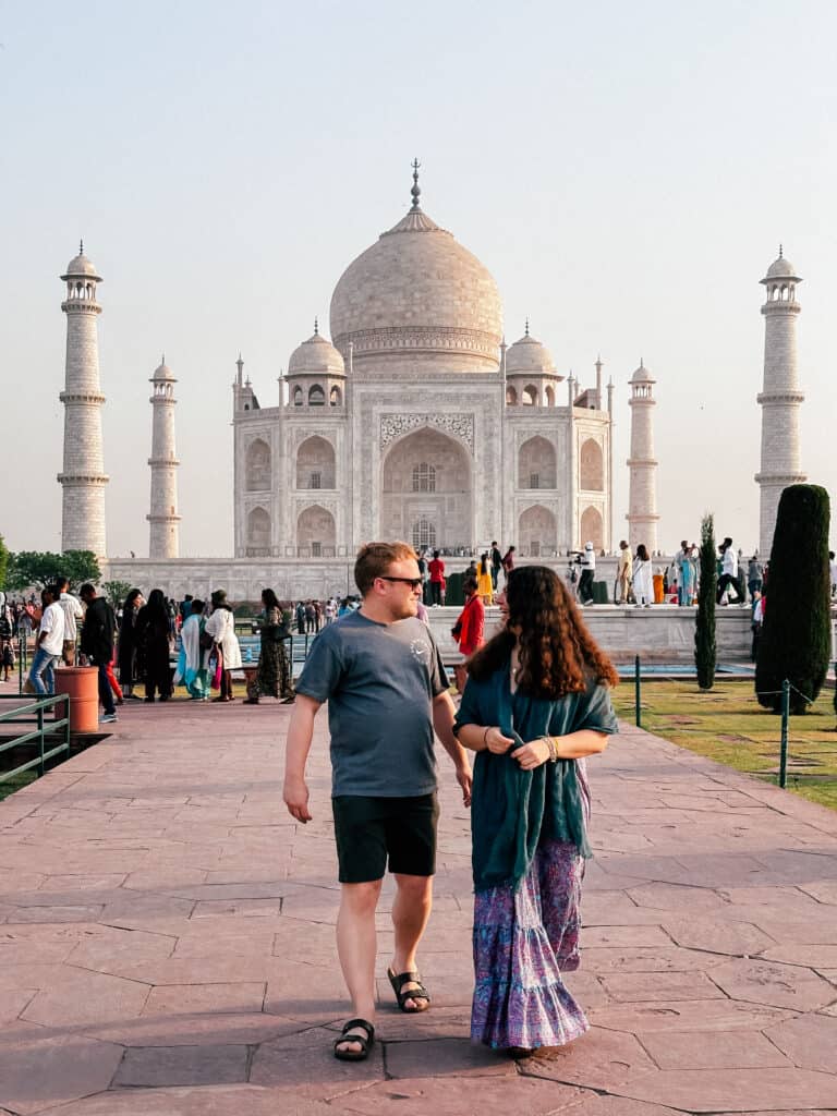 Is India a safe country to travel? Couple walking in front of Taj Mahal in Agra, India