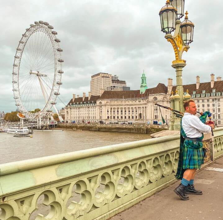 Pipe Player in Westminster bridge overlooking London eye and the Marriott County Hall