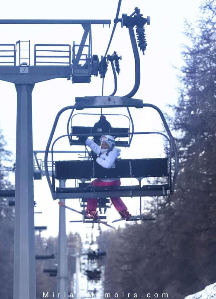 Women enjoying a ski lift ride in snowy landscape, winter sports, family fun, snow adventure, outdoor activity.