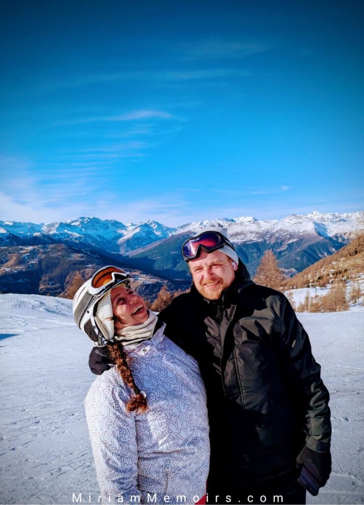 Couple in Sauze d'Oulx ski resort in Italy together smiling with mountains in the background